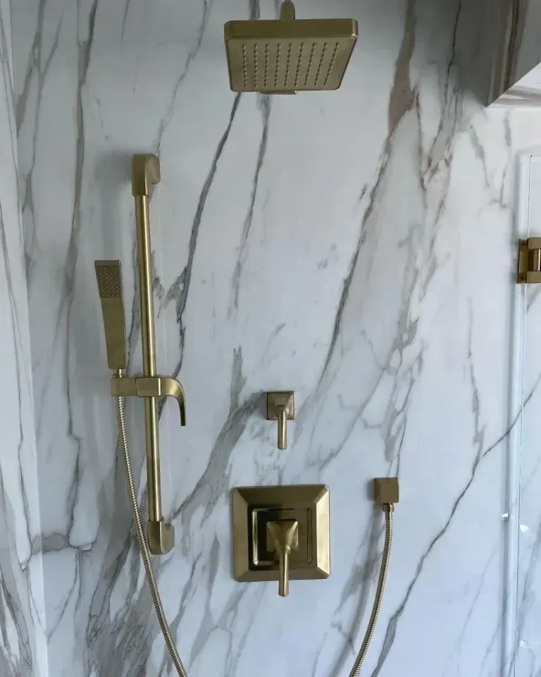 Gold shower set on white marble-tile bathroom wall