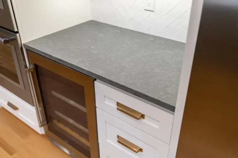 Modern kitchen countertop with gray surface, white drawers, and a built-in oven on the left
