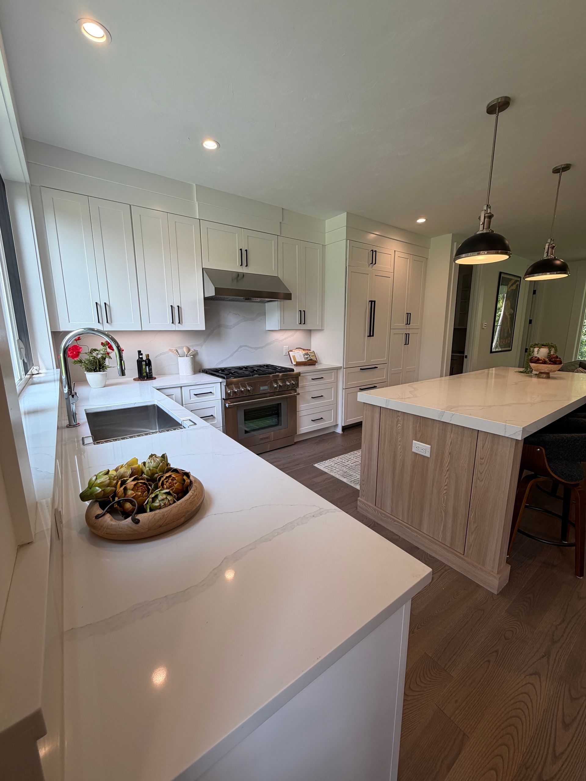 Bright, modern kitchen with white cabinets, island, and pendant lights