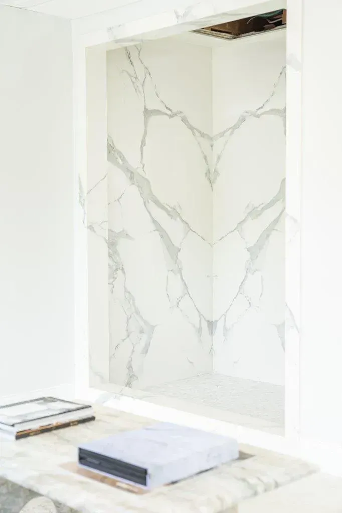 Minimalist white room with a marble-patterned wall and two stacked books on the floor
