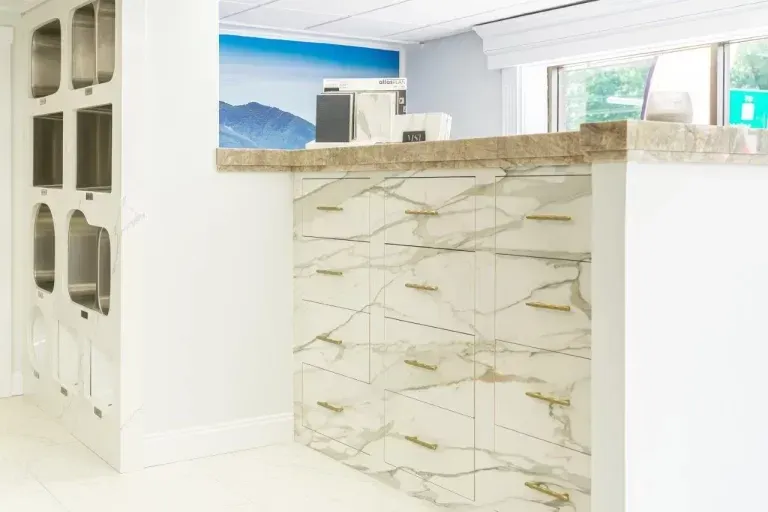 Modern bright kitchen with white cabinets, marble island, and ocean view through the window