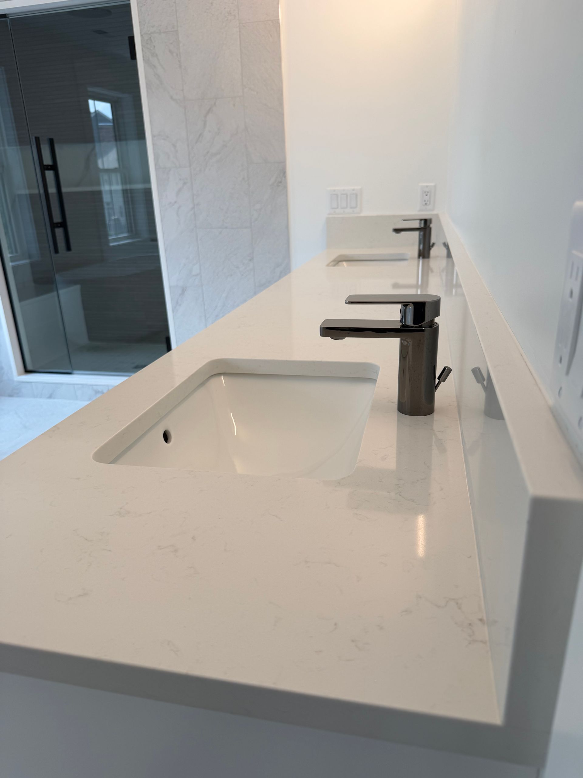 Modern bathroom sink with white countertop and black faucet in a minimalist interior