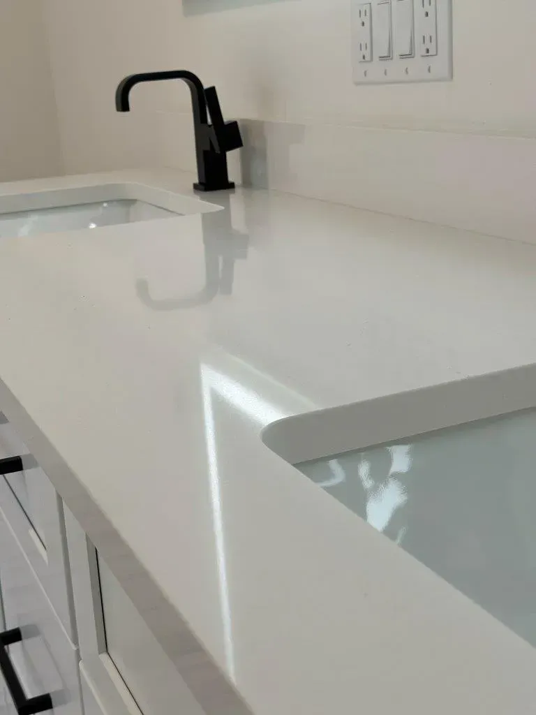 Modern white bathroom vanity with a glossy countertop, black faucet, and sink cutout