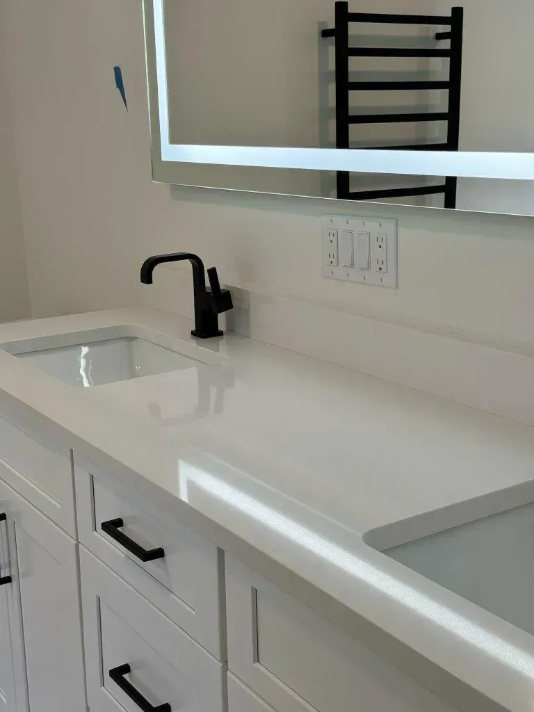 White bathroom vanity with double sinks, black faucet, and large mirror above.