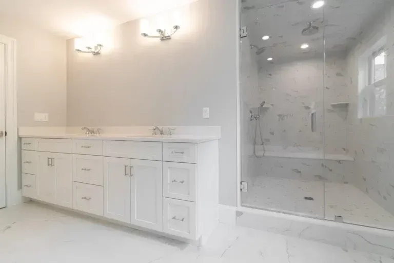 Bright white bathroom with double vanity, large mirror, and glass walk-in shower