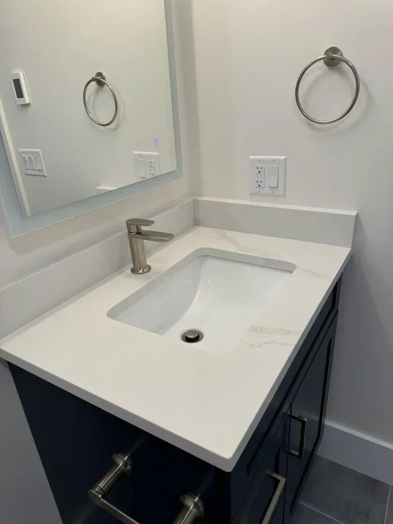 Modern white bathroom vanity with sink, mirror, chrome faucet, and towel ring