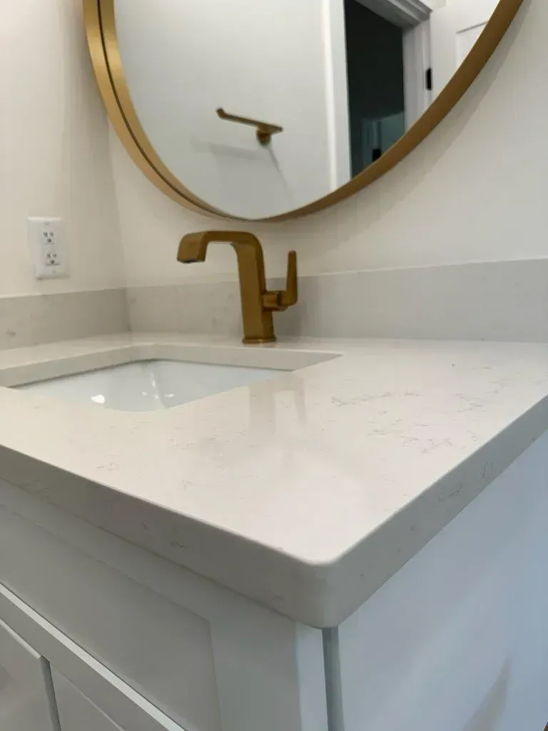 Modern white bathroom vanity with gold faucet and round mirror