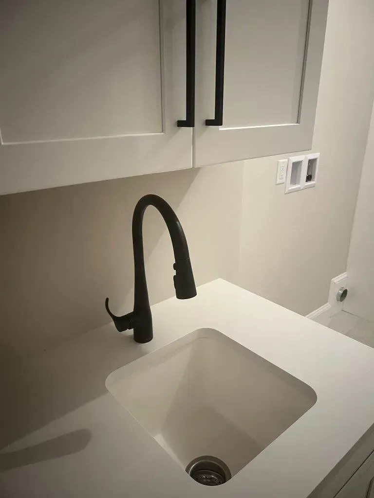 Modern bathroom sink with black faucet and white cabinets above