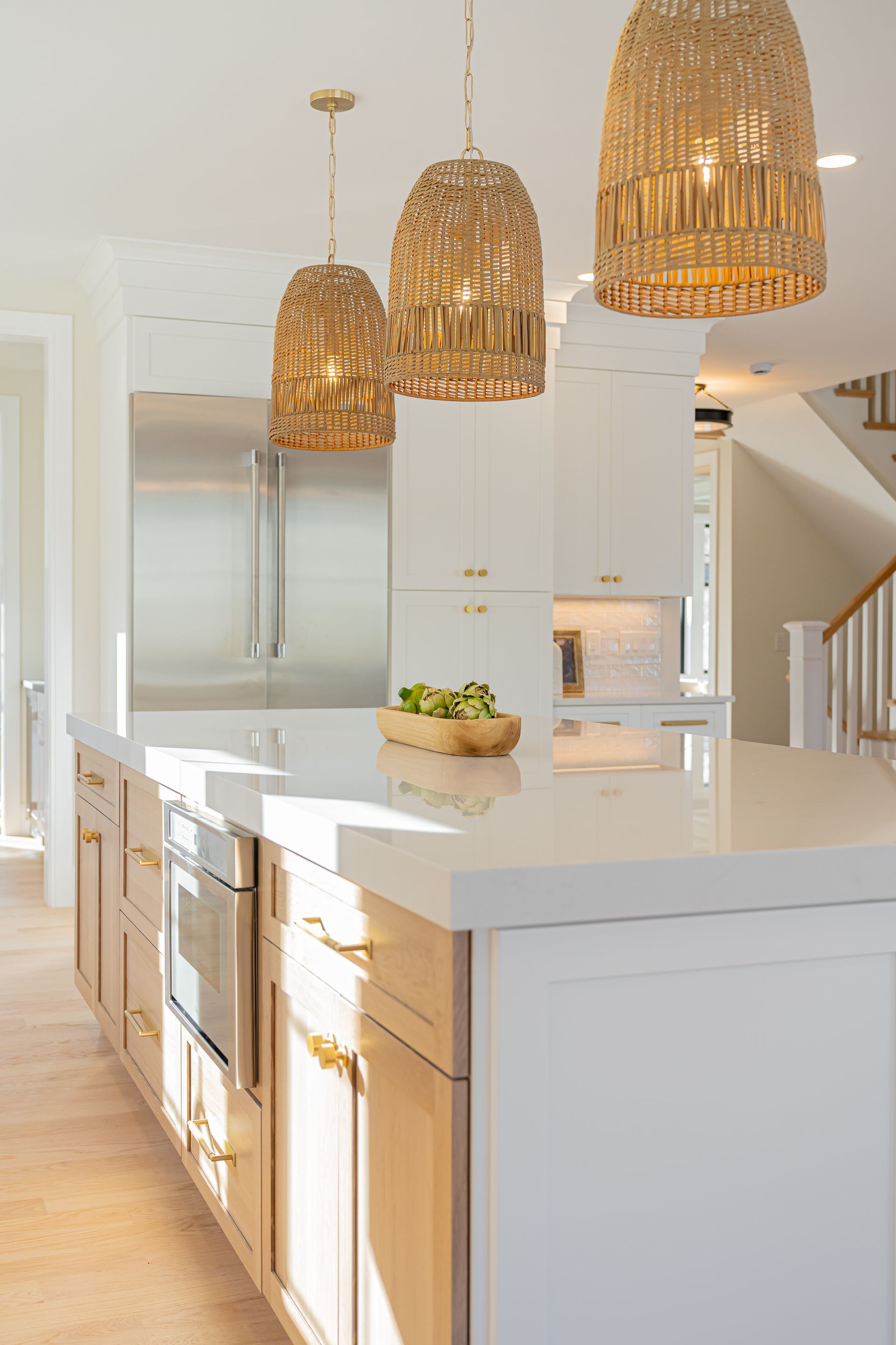 Bright white modern kitchen with island, wicker pendant lights, and wooden flooring