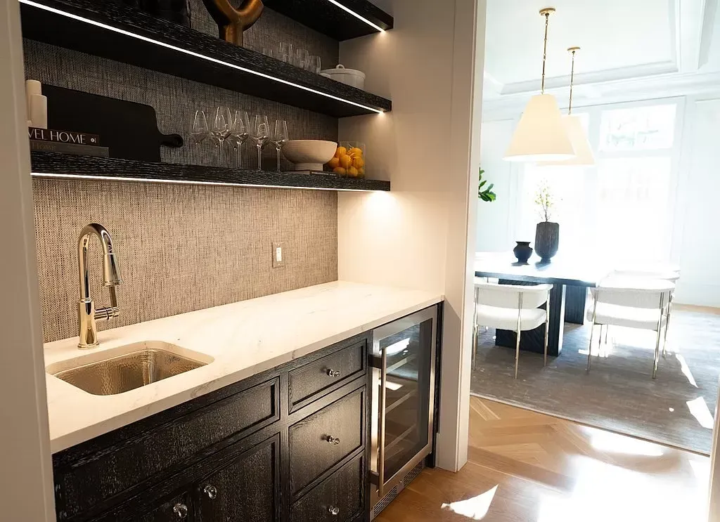 Modern kitchen with dark cabinets, white countertop, open shelves, and a view into a bright dining area.