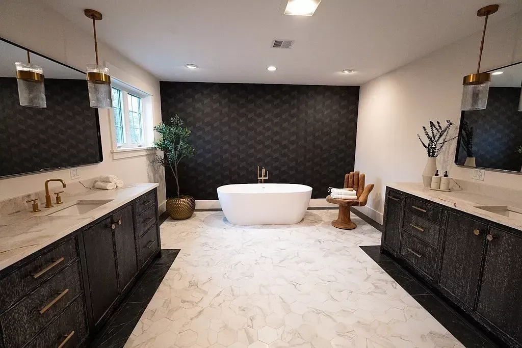 Elegant bathroom with a freestanding tub, dark cabinets, and white marble flooring.