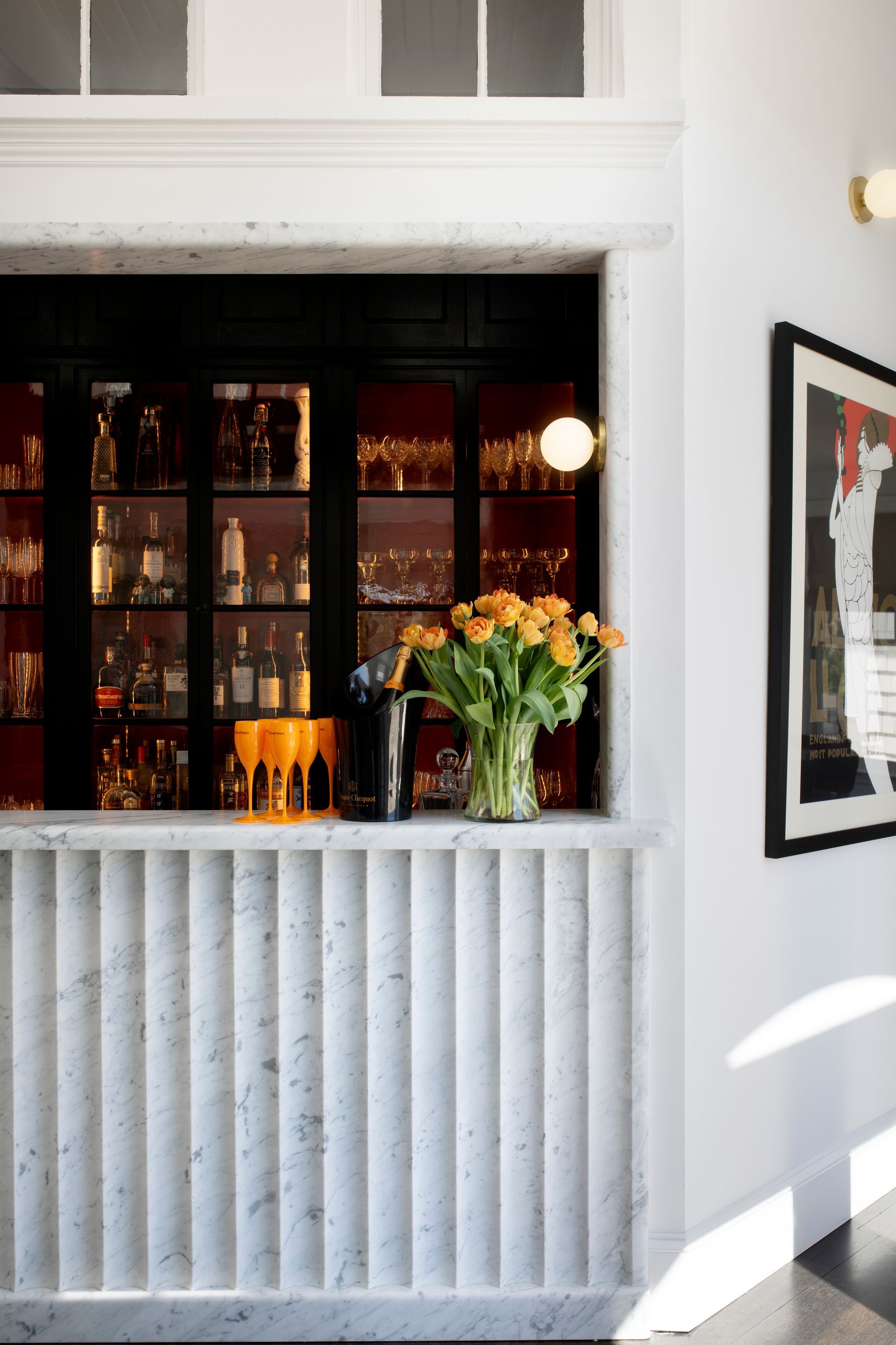 White storefront window with black panes, flowers on the sill, and a framed artwork on the wall