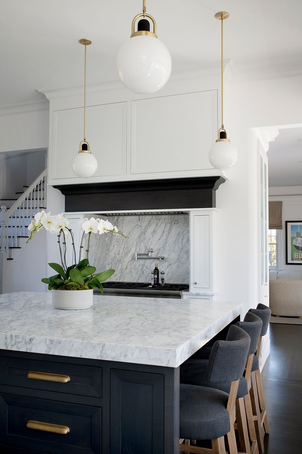 Modern kitchen with marble island, dark cabinetry, pendant lights, and a white orchid centerpiece