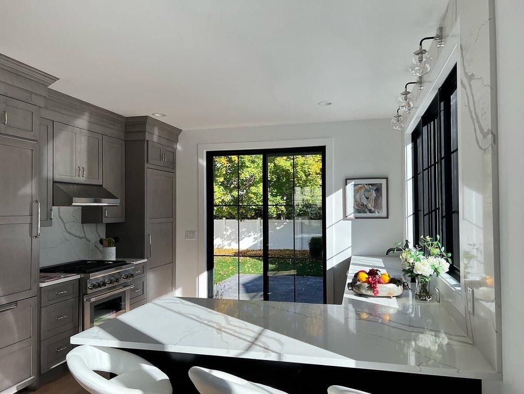 Bright modern kitchen with stainless appliances, white island, and sliding glass doors to a patio.
