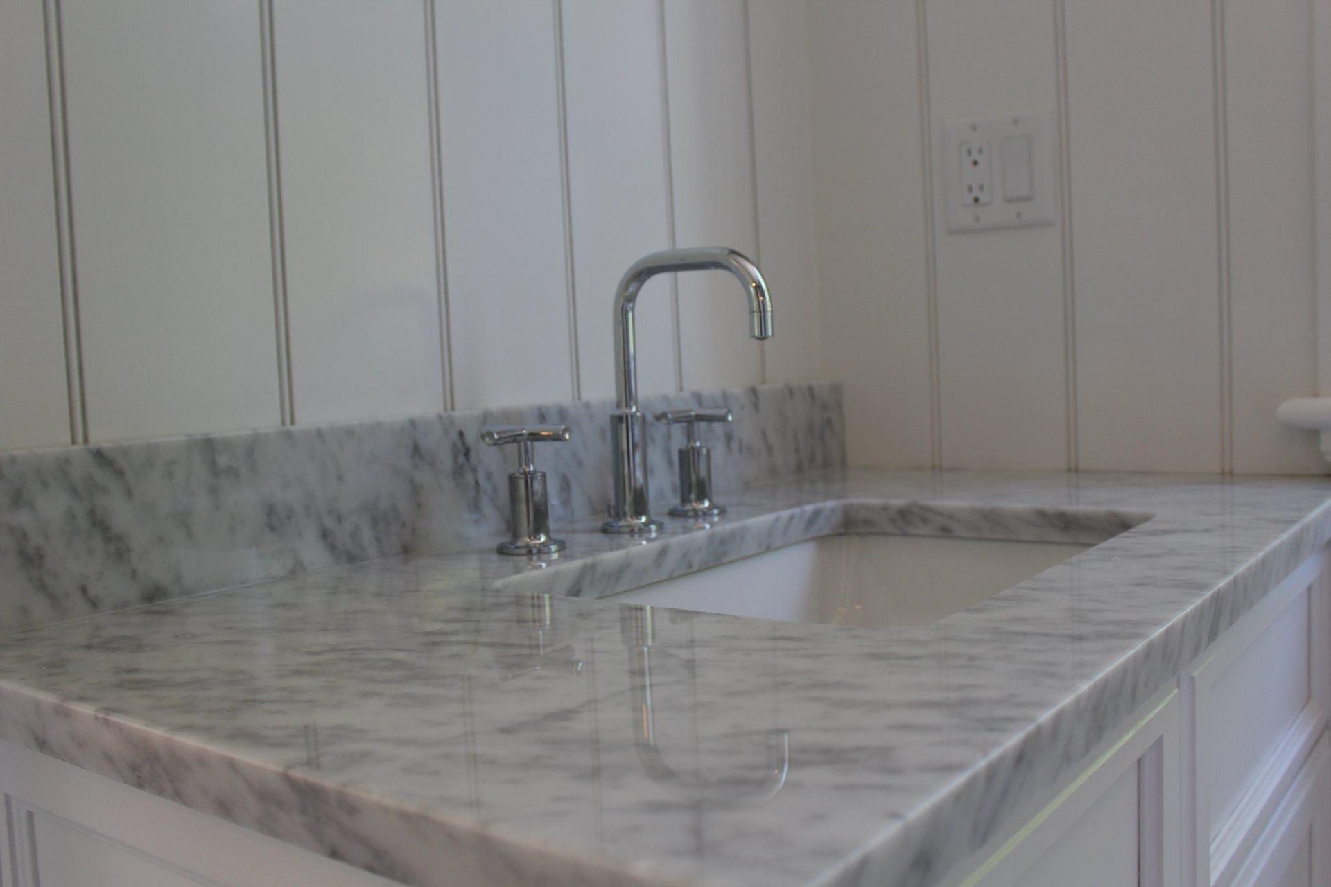 Marble kitchen countertop with built-in sink and chrome faucet against white cabinets