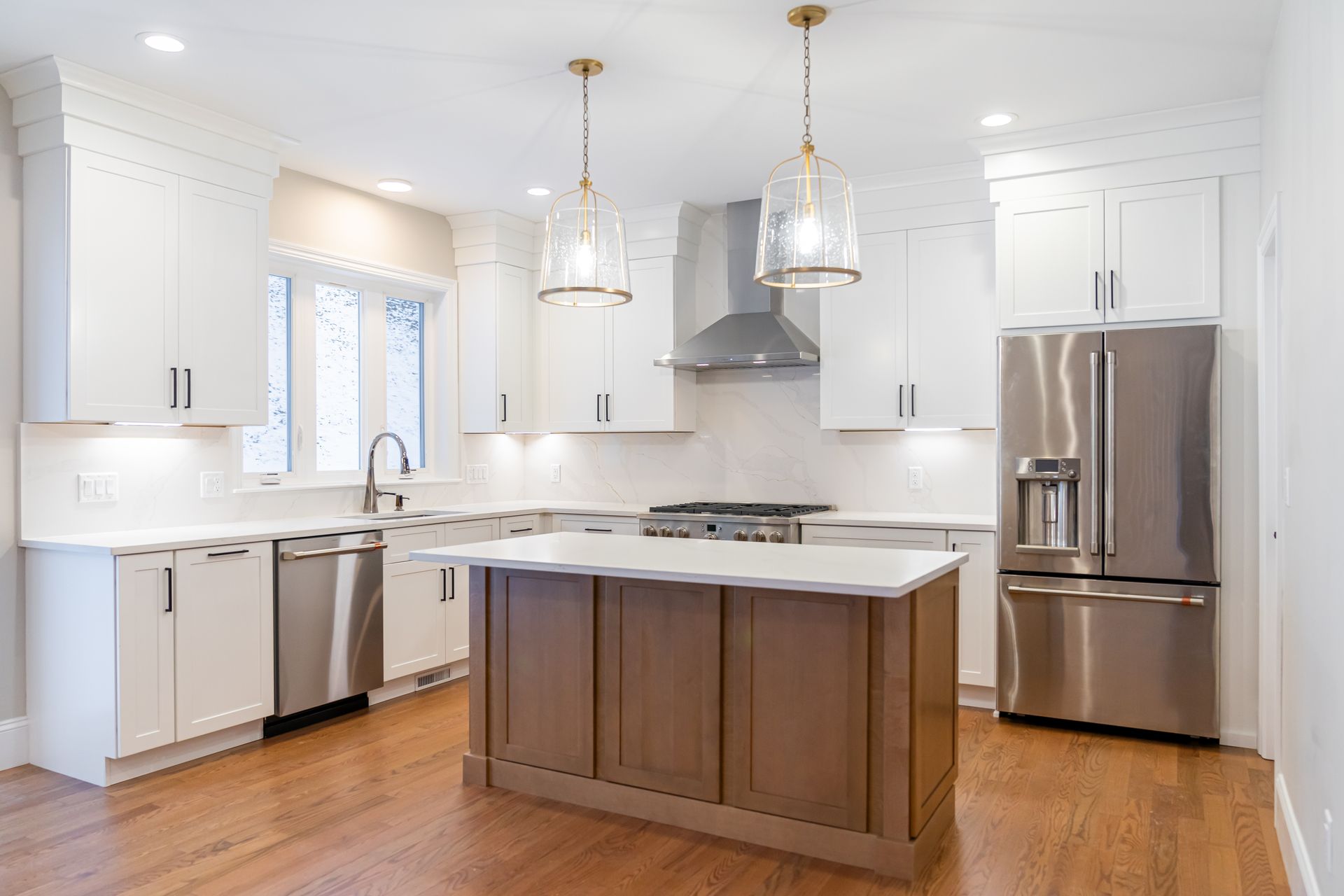 Bright modern white kitchen with stainless steel appliances and a wooden island.