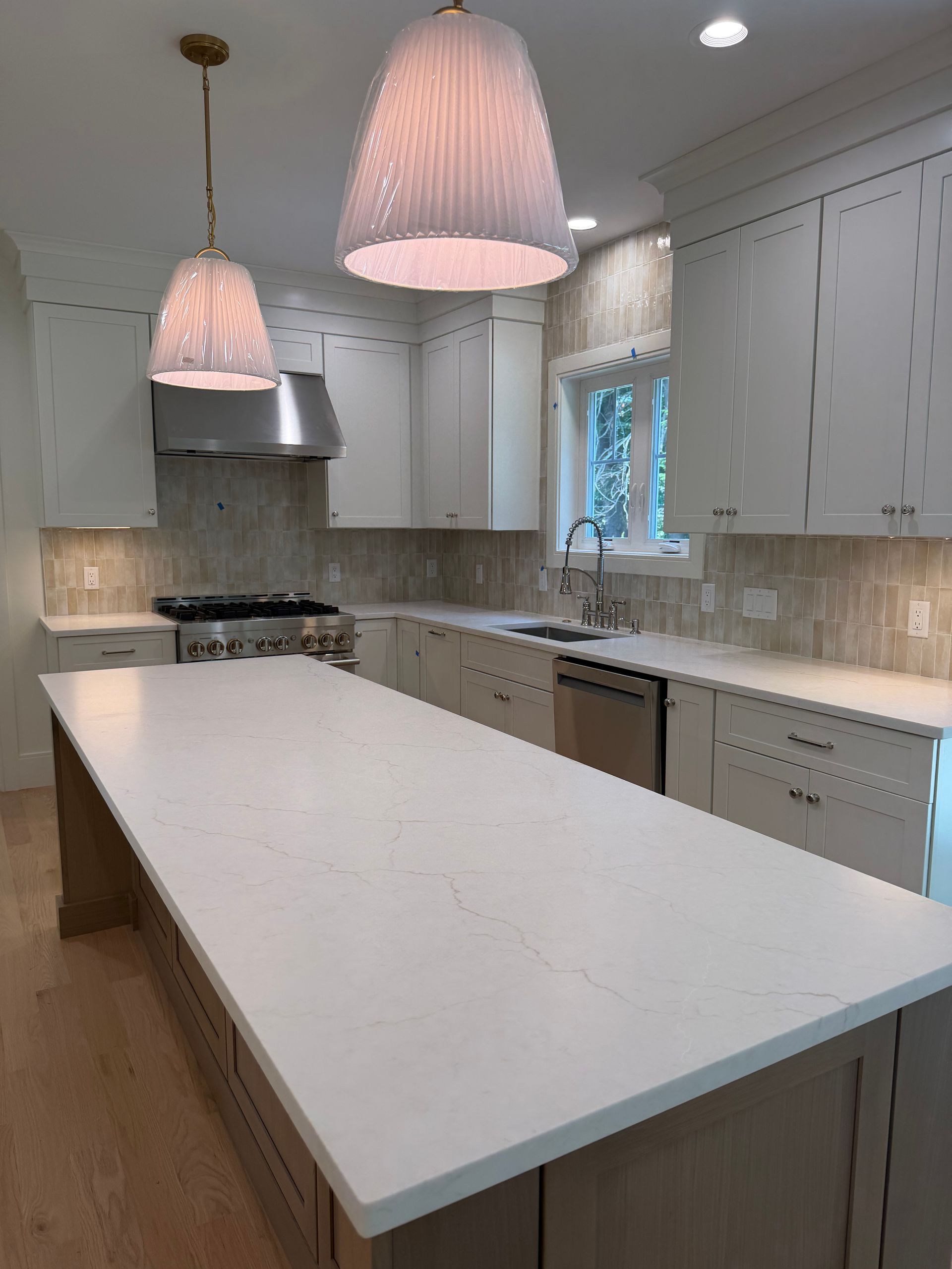 Bright modern kitchen with white island, gray cabinets, and pink pendant lights