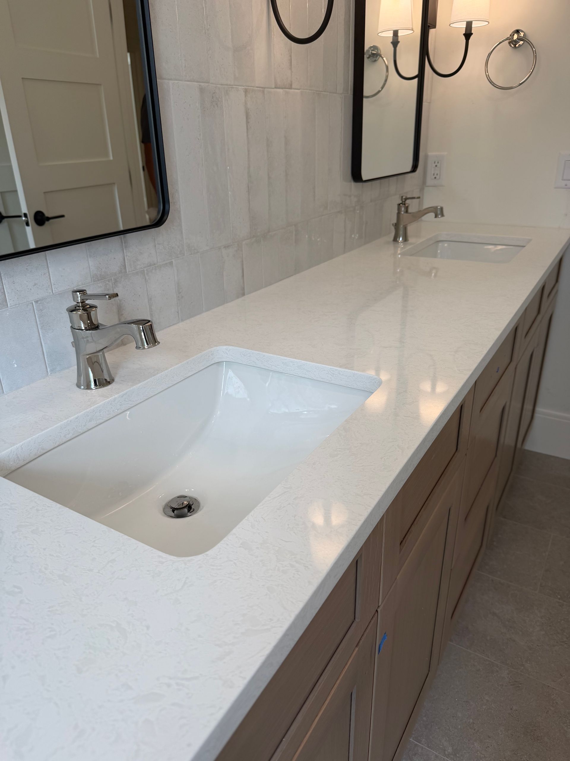 Modern bathroom vanity with white quartz countertop, undermount sink, chrome faucet, and wall mirror above.