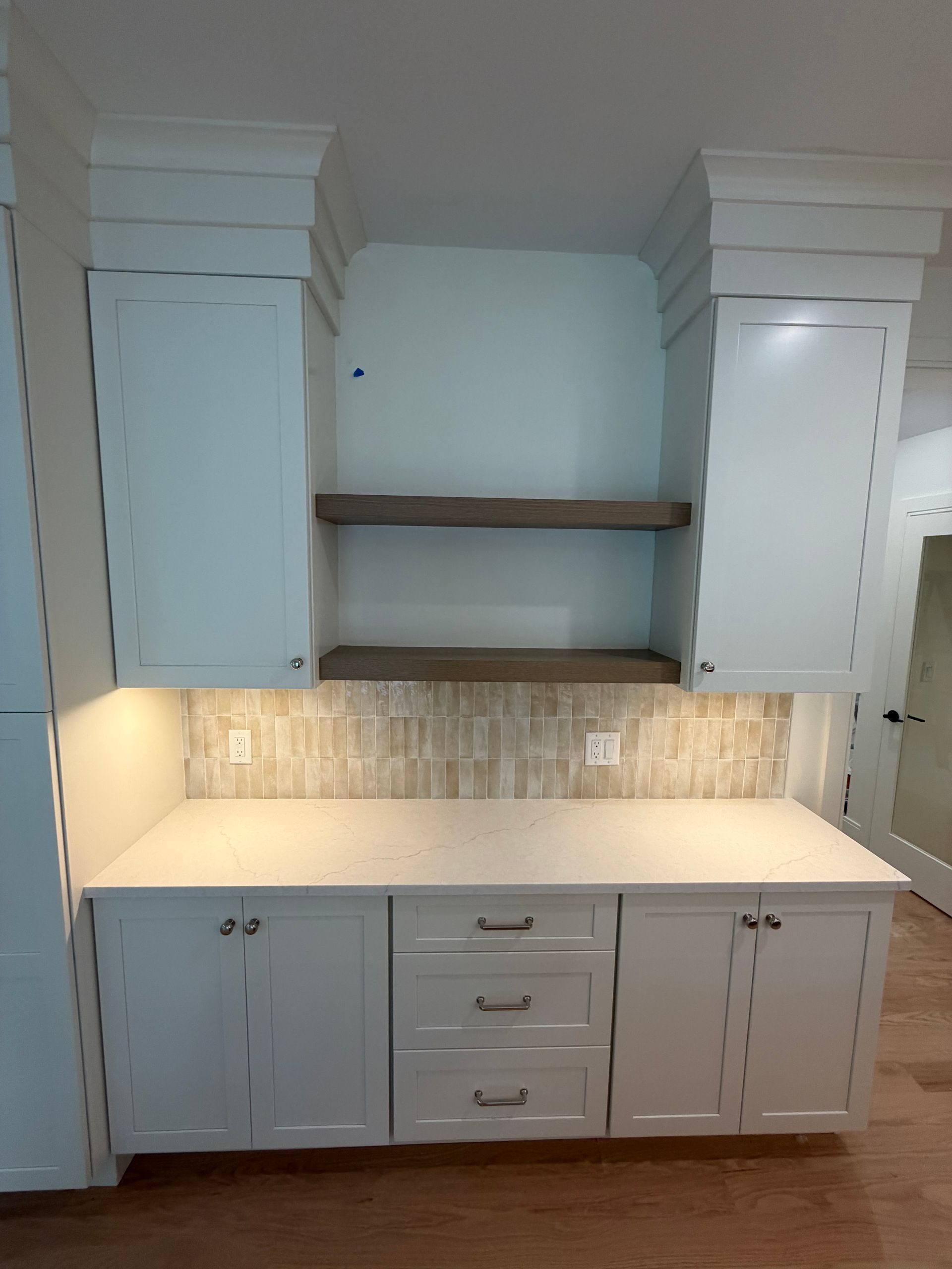 Built-in white kitchen cabinets with countertop, open shelves, and under-cabinet lighting