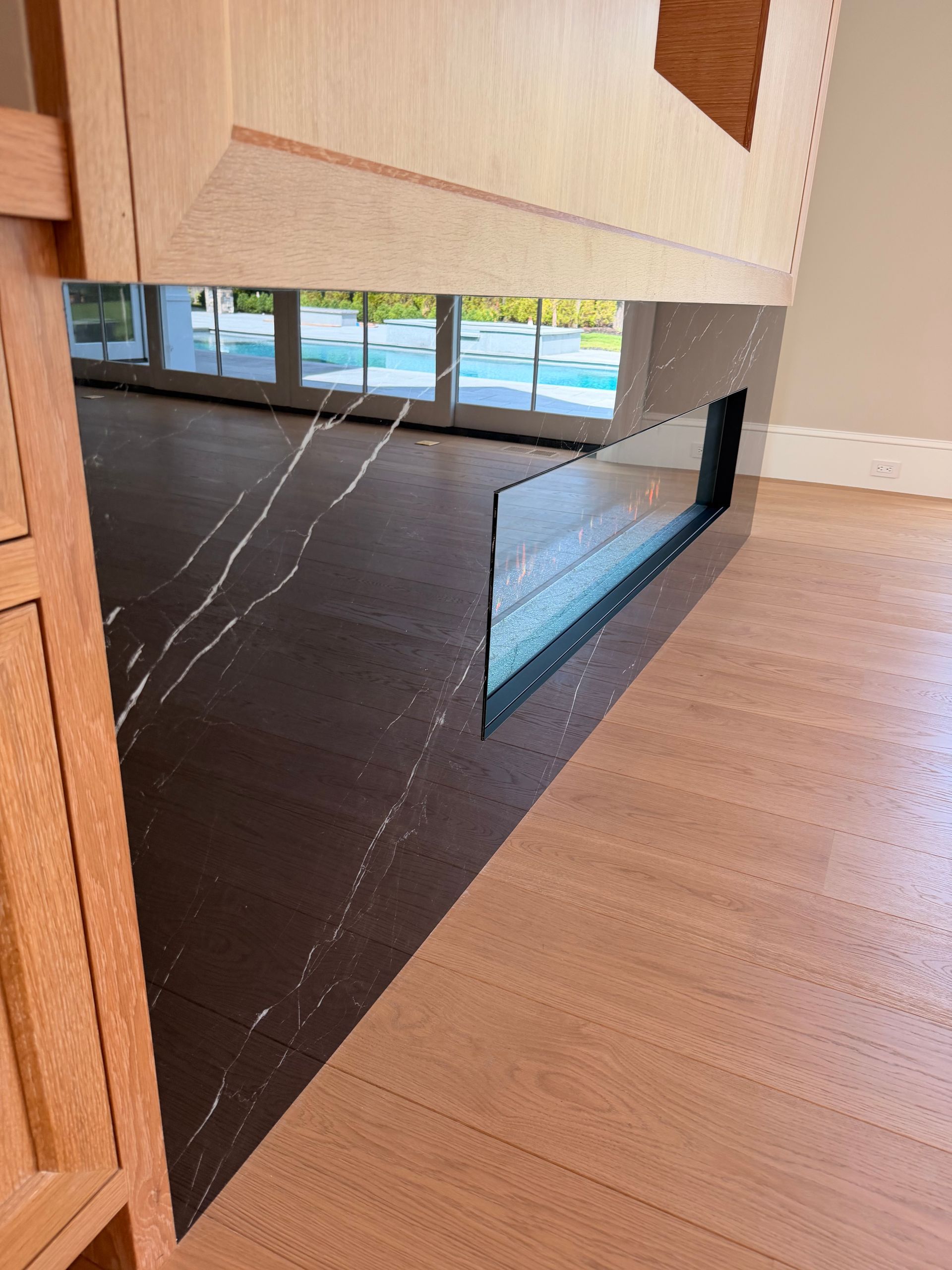 Modern staircase with dark triangular steps and a glass wall overlooking a bright interior.