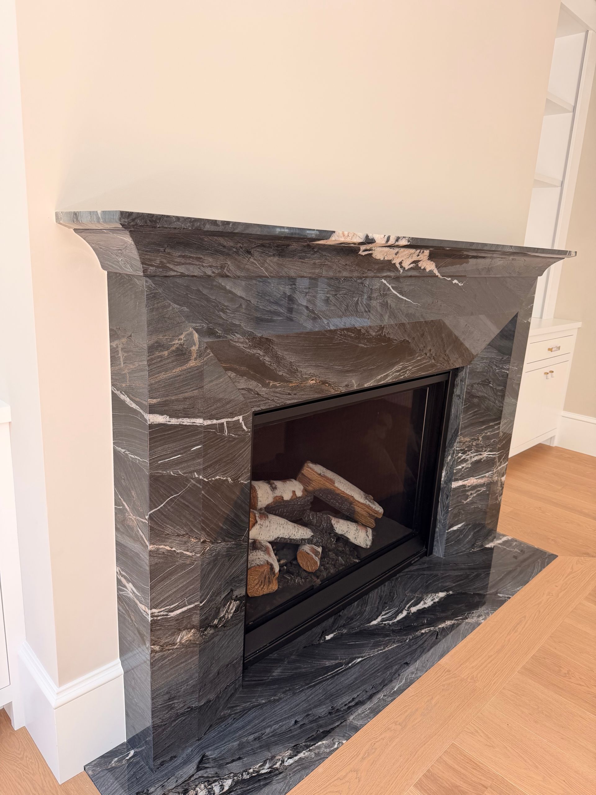 Dark marble fireplace with glass firebox in a beige room