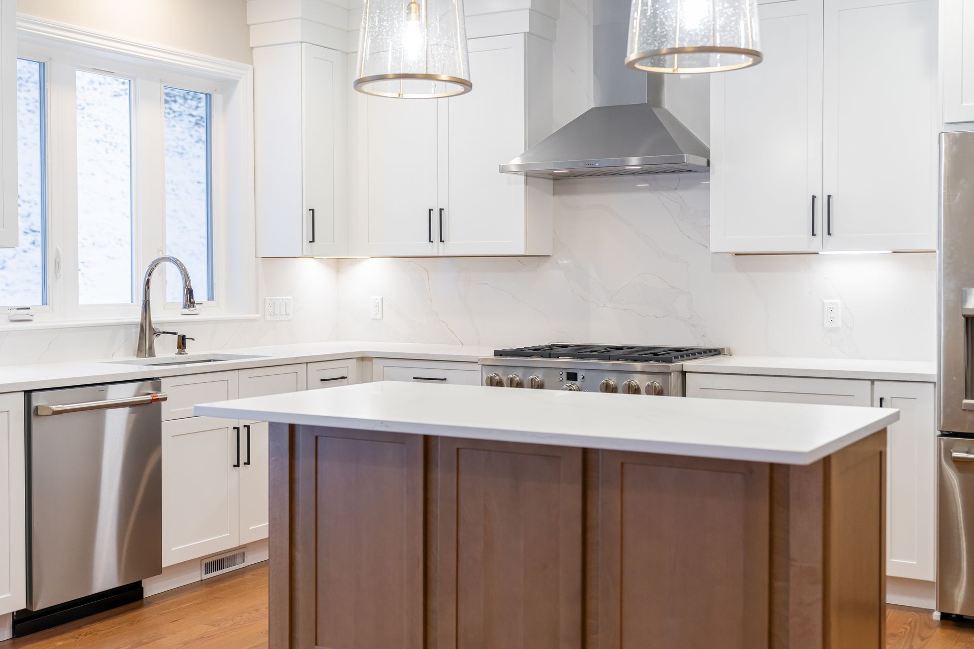 Bright modern kitchen with white cabinets, stainless appliances, and a wood island with a white countertop