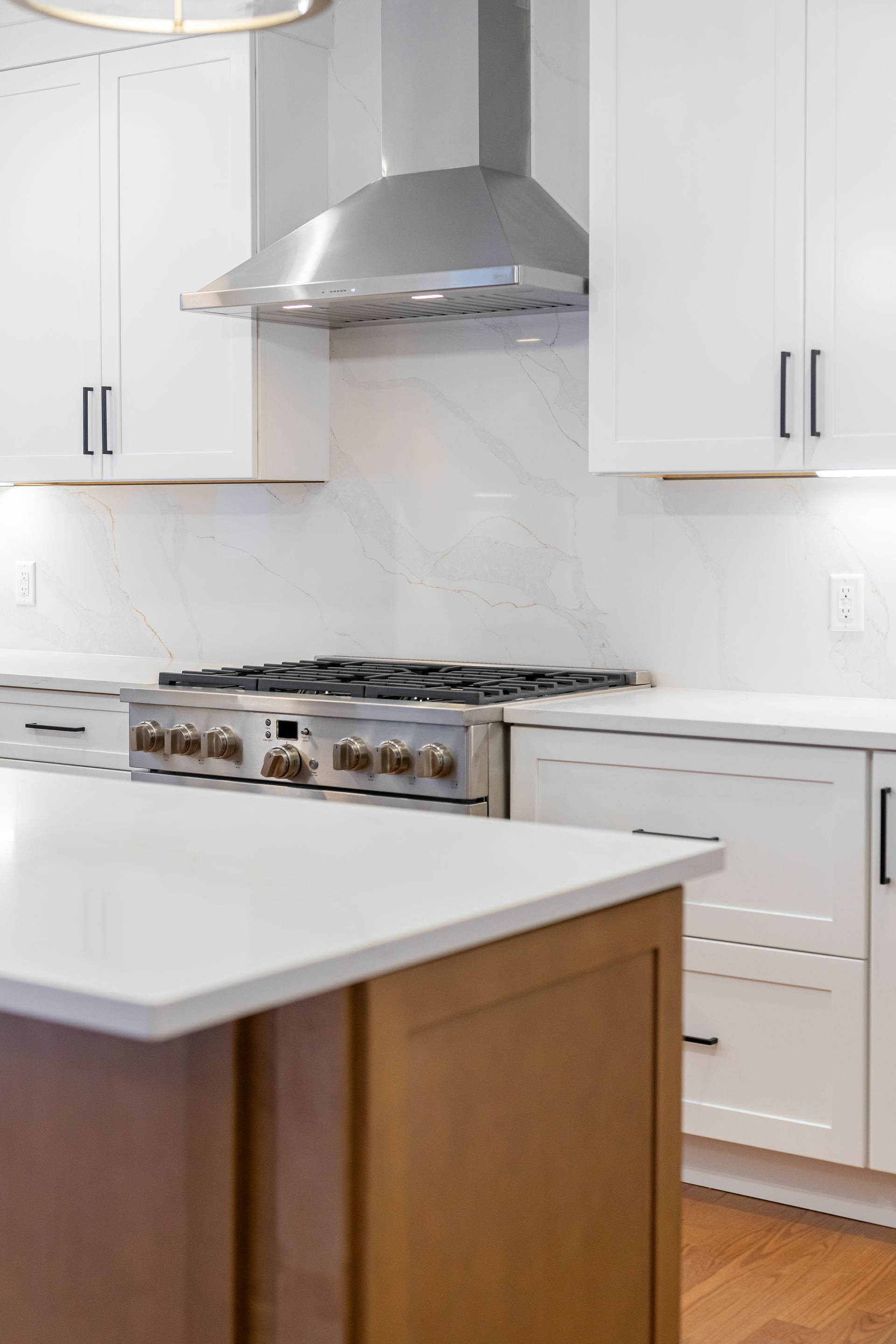 Modern kitchen with white cabinets, stainless steel range hood, and a white island countertop