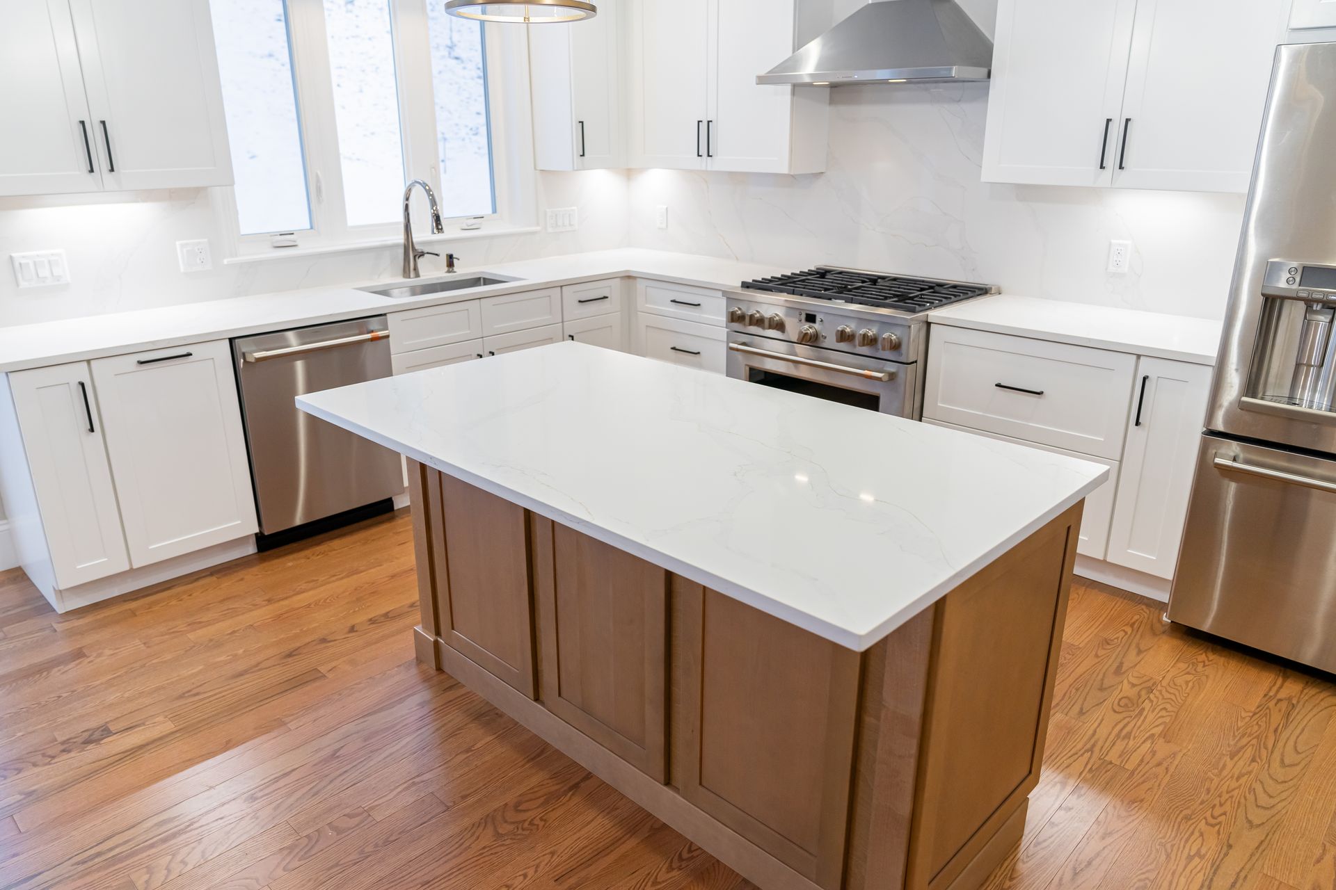 Bright modern white kitchen with island, stainless steel appliances, and hardwood floors