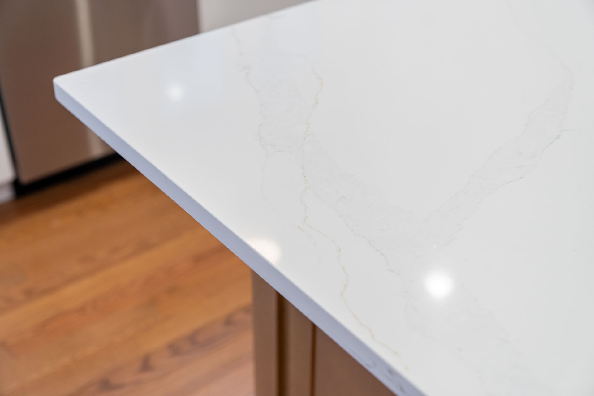 White marble countertop corner with light wood floor in the background