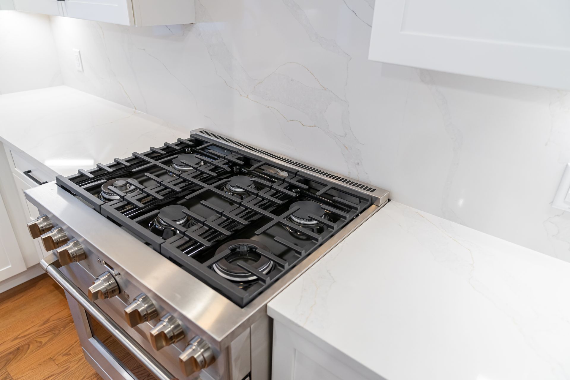 Modern kitchen with a stainless steel gas cooktop on a white countertop and backsplash