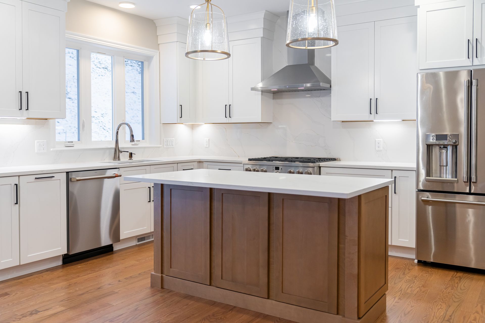 Bright modern kitchen with white cabinets, stainless appliances, and a wood island