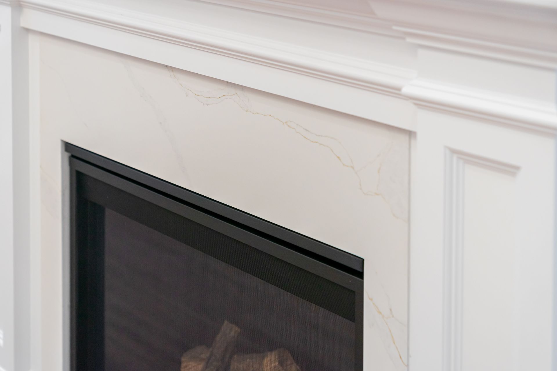 White marble fireplace surround with black glass firebox and subtle gold veining