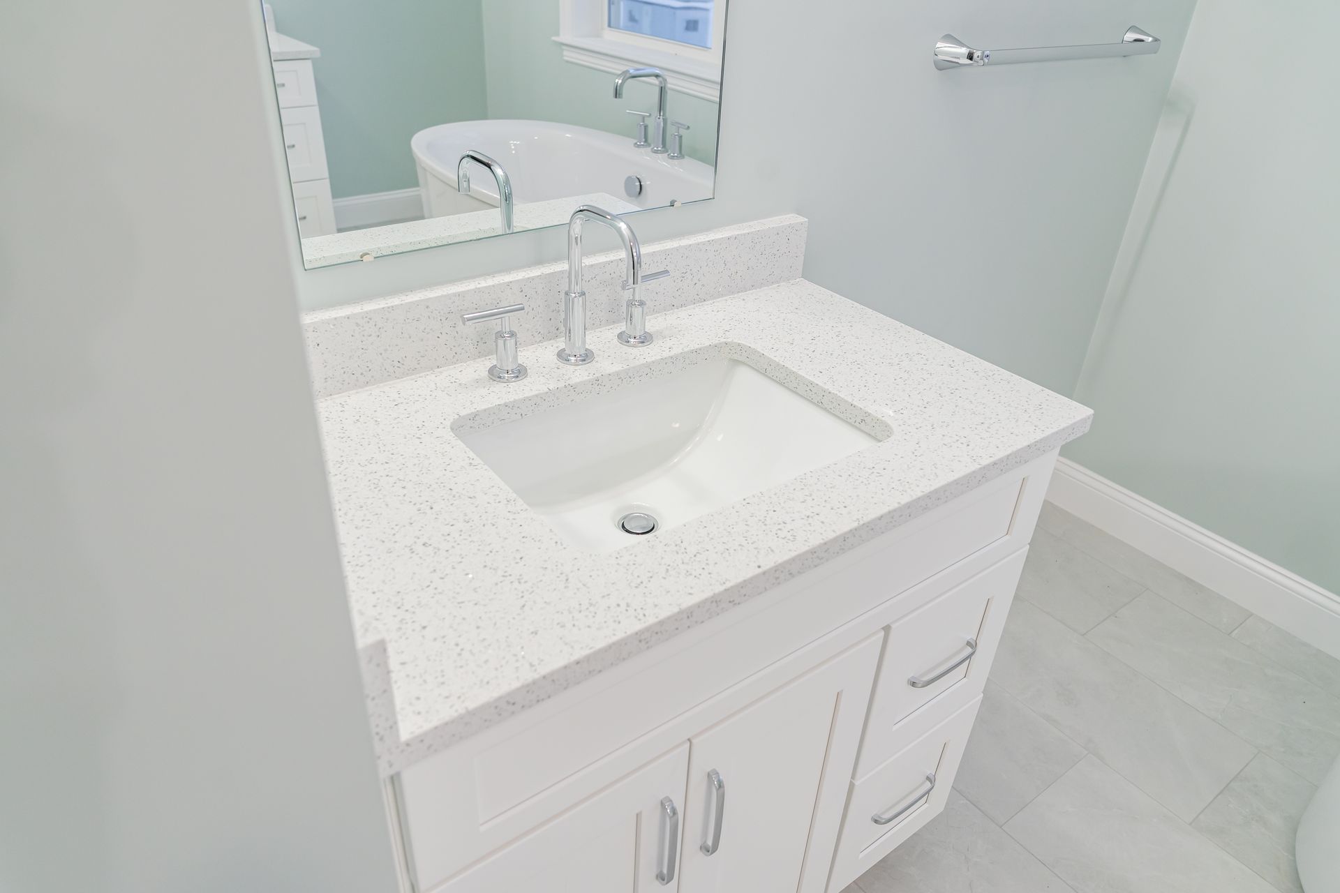 White bathroom vanity with sink, mirror, and light gray walls and floor.