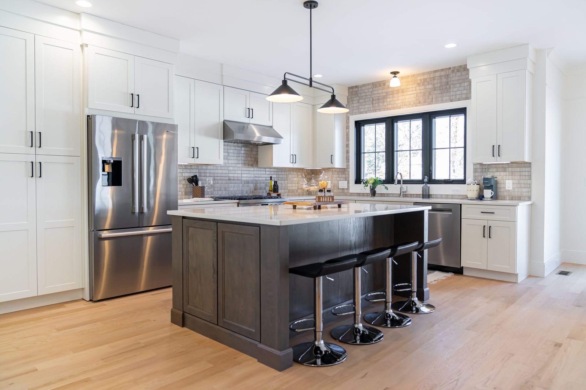 Bright white kitchen with island, pendant lights, and large window over the sink