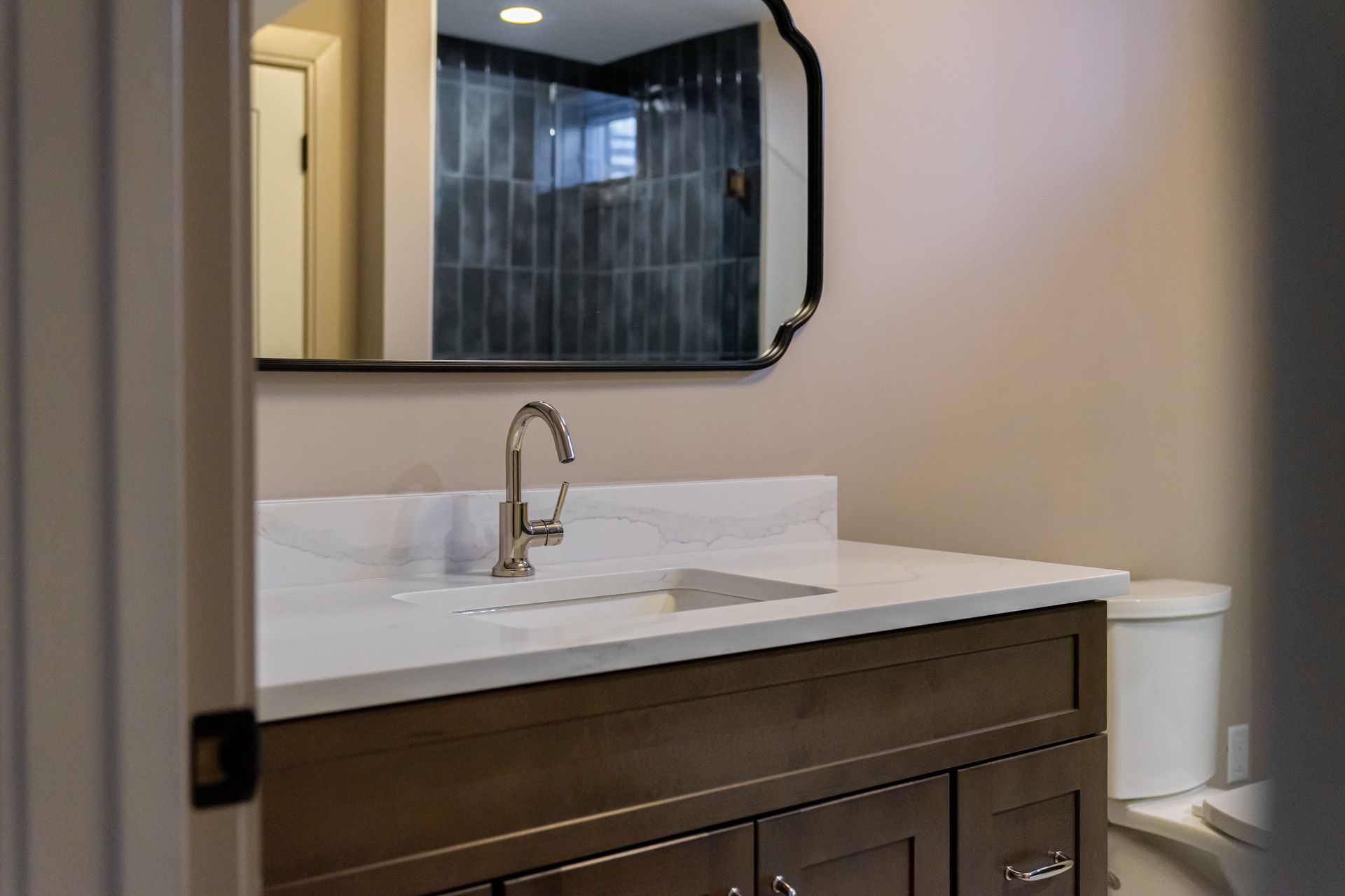 Modern bathroom vanity with white sink, dark wood cabinet, and black-framed mirror