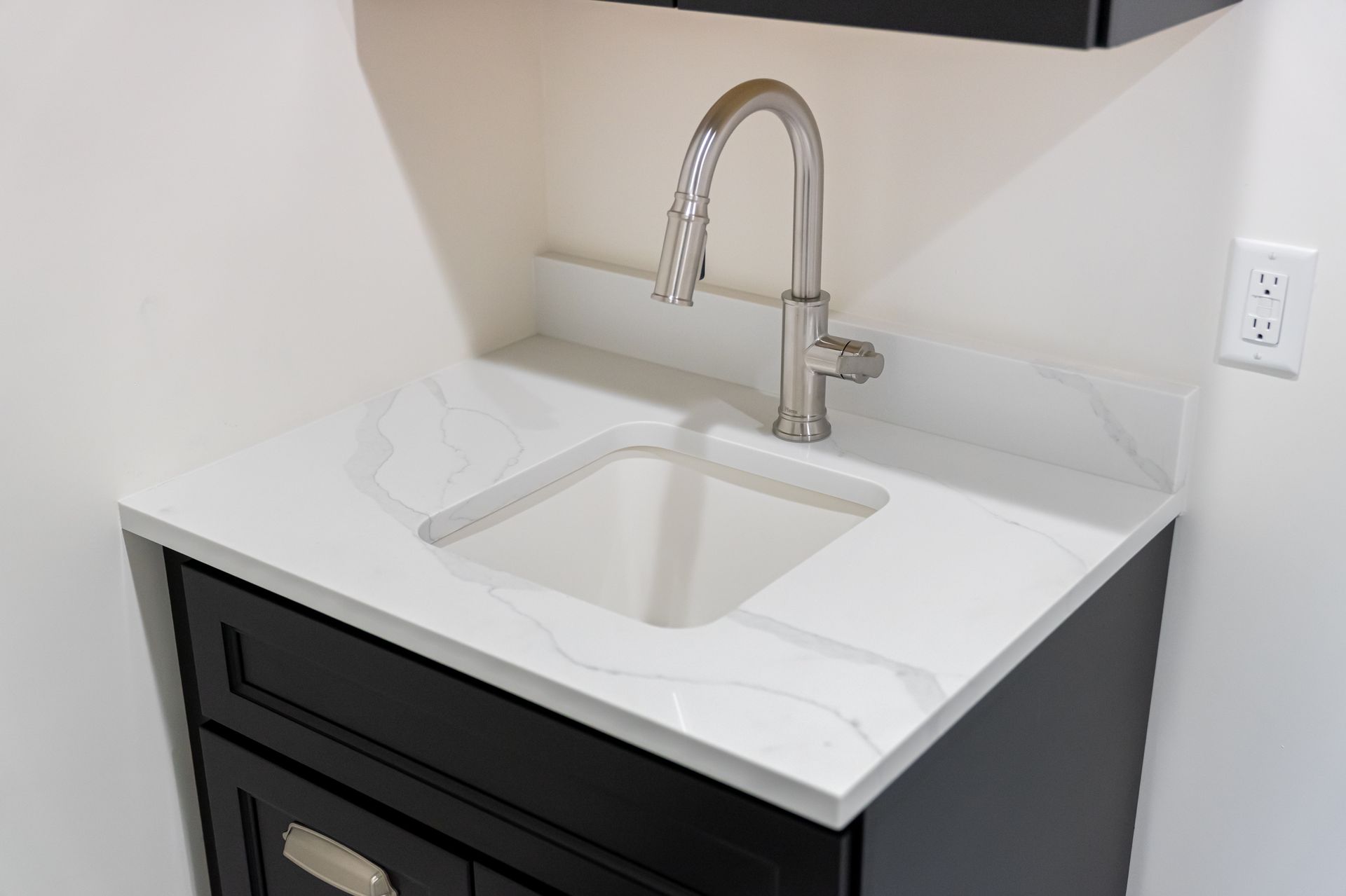 Modern bathroom vanity with white sink, chrome faucet, and black cabinet under a mirror