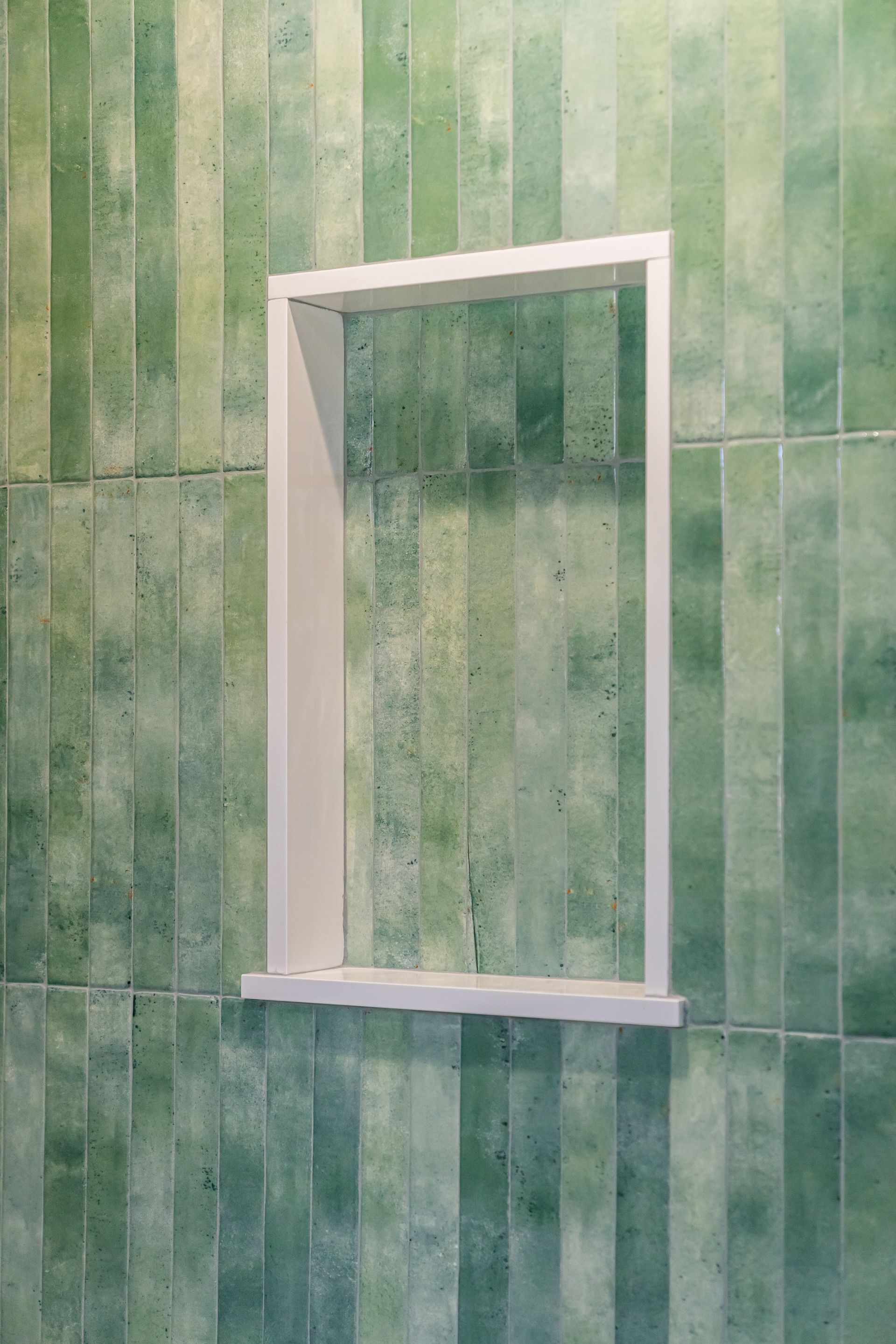 White window frame in a green tiled wall, seen from the side.