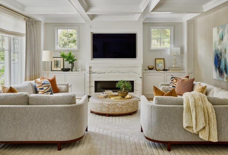 Bright living room with white sofas, a large TV, fireplace, and soft neutral decor