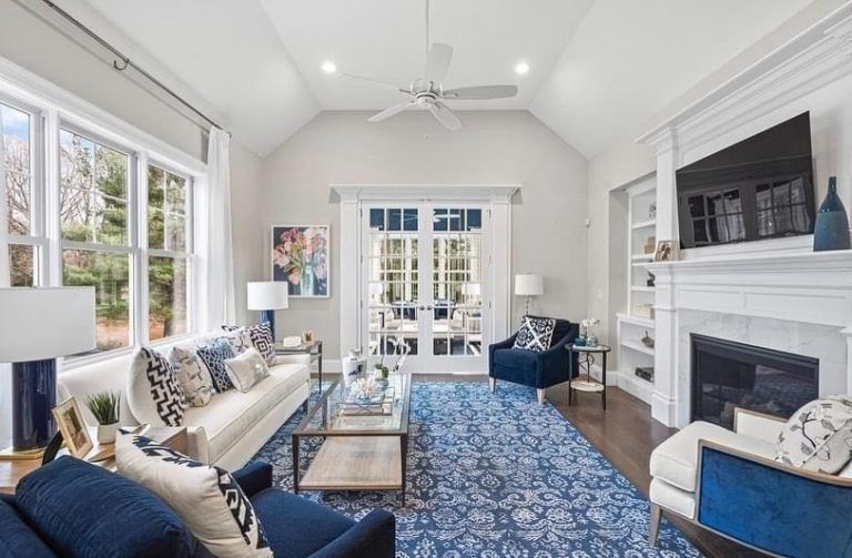 Bright living room with blue accents, fireplace, large windows, and French doors to a patio