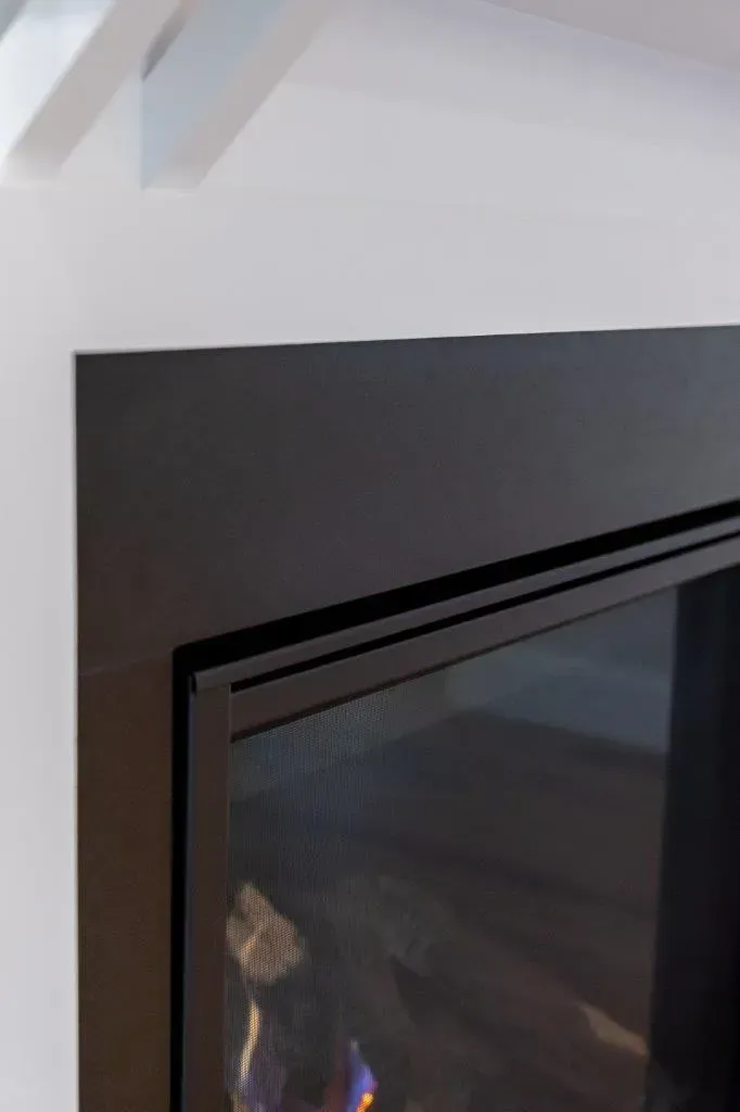 Modern black fireplace against a white wall with a reflective glass front