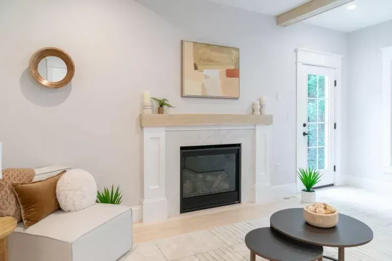 Bright living room with a white fireplace, beige sofa, round coffee table, and front door.