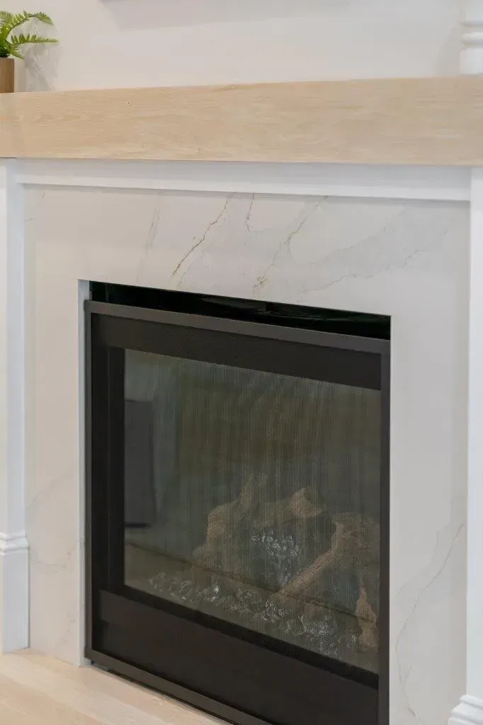 Modern black glass fireplace set in a white mantel with a light wood shelf above