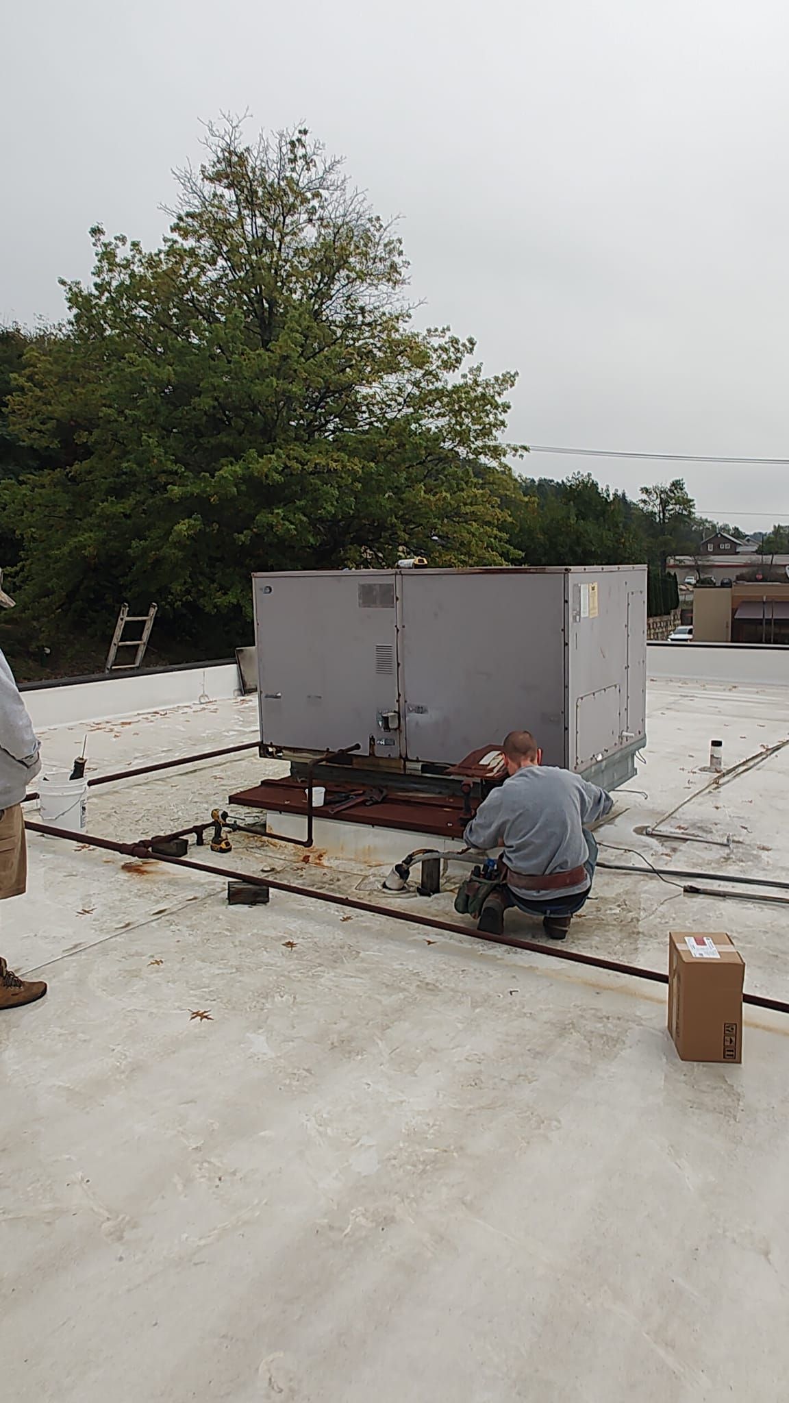 A man is kneeling on a roof working on wiring