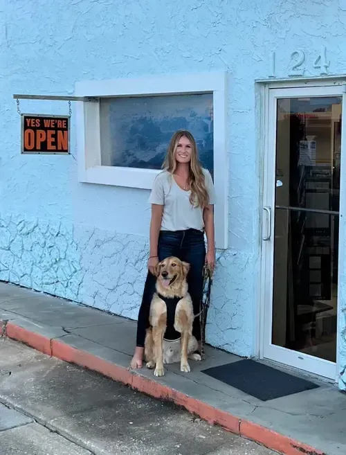 Man with beard, holding head, wearing gray jacket and cable-knit sweater, looking distressed.