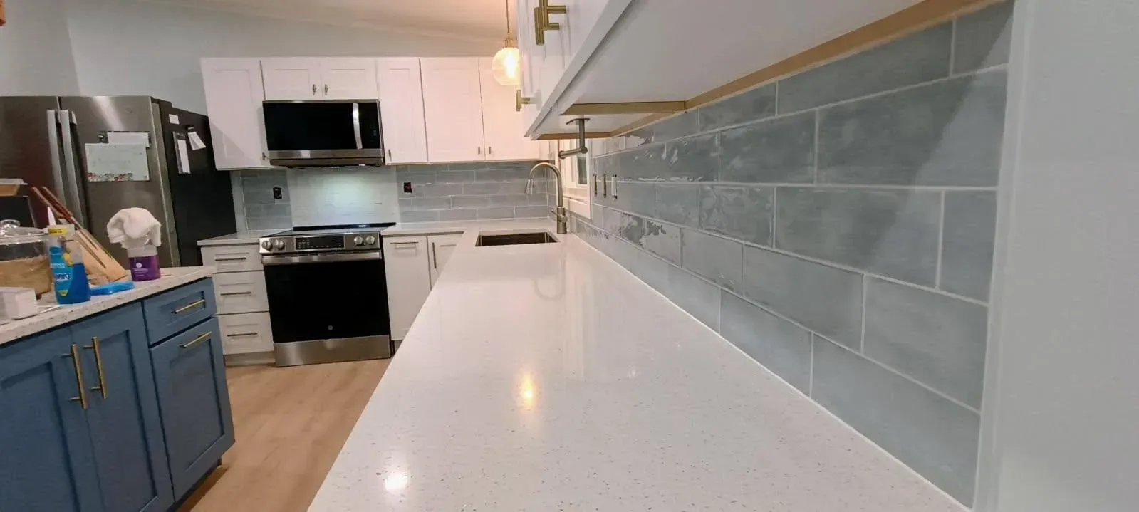 Kitchen with white cabinets, blue cabinets, light wood floor, and gray backsplash.