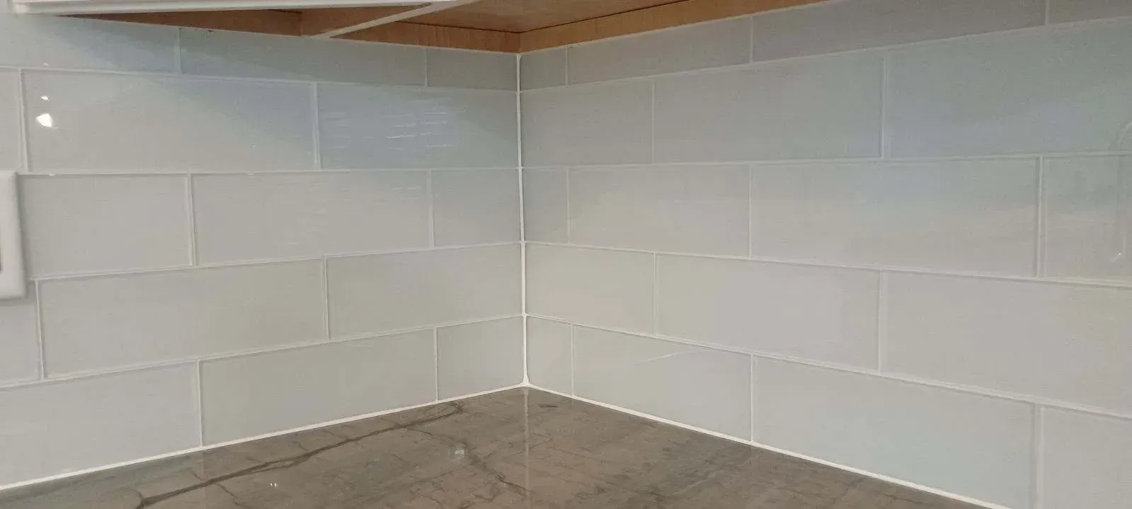 Kitchen corner with light blue rectangular tiles on walls, gray countertop.