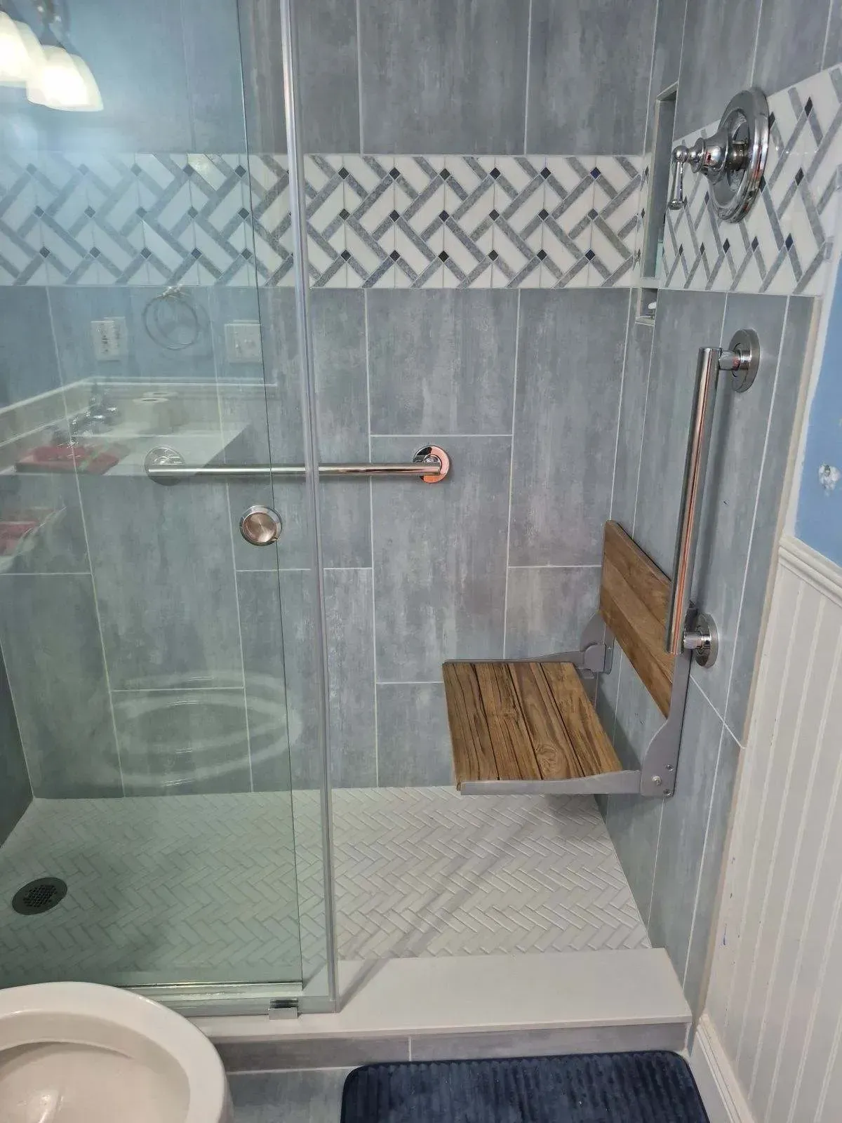 Accessible shower with fold-down seat, grab bar, and blue tile.