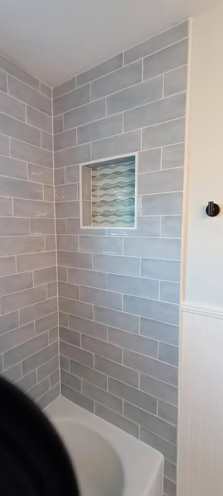 Gray tiled shower with inset shelf.