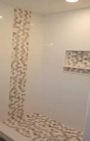 Bathroom with white walls and hexagonal mosaic tile strip and floor, built-in shelf.