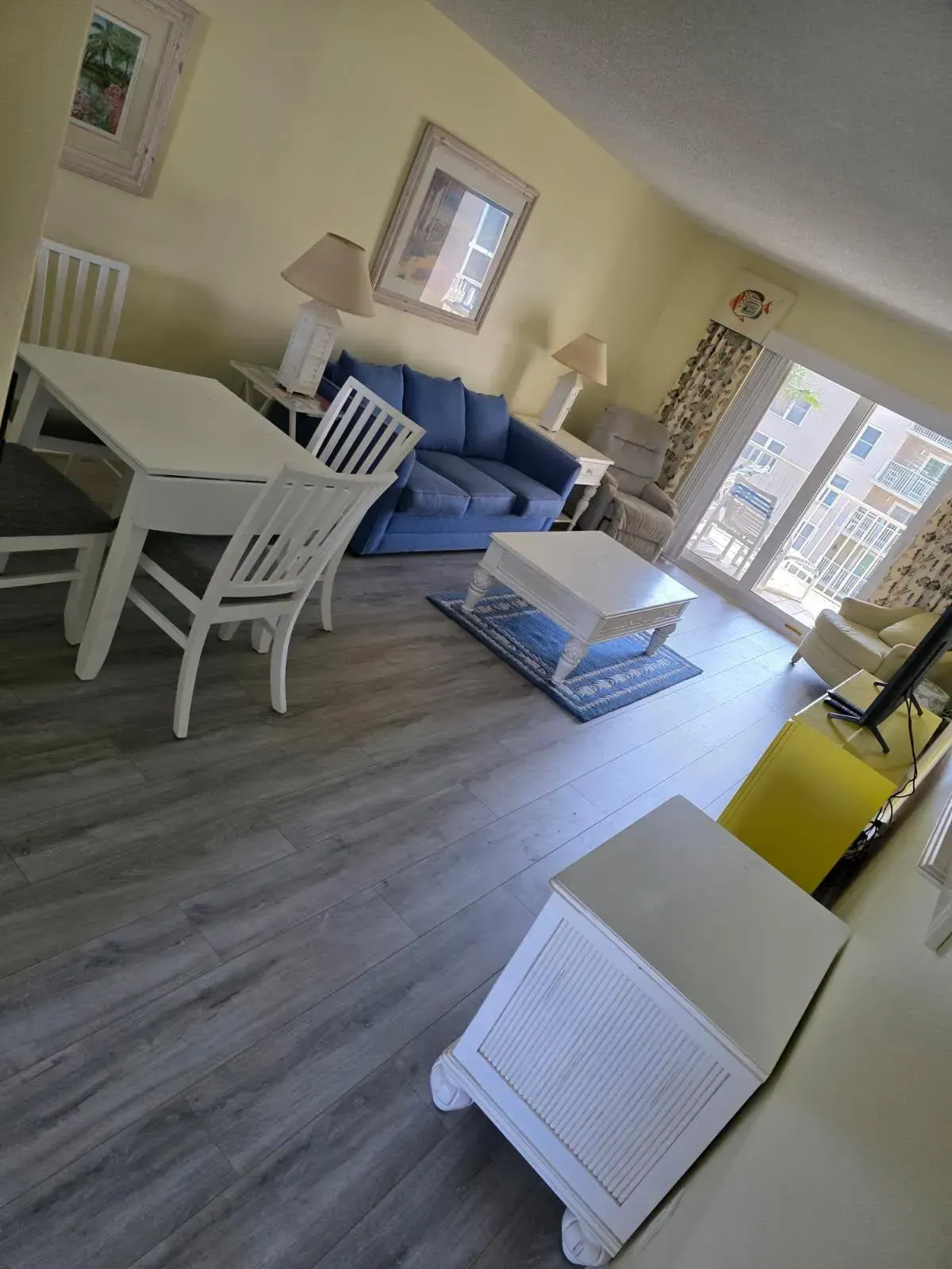 Living room with white furniture, blue sofa, and sliding glass doors.